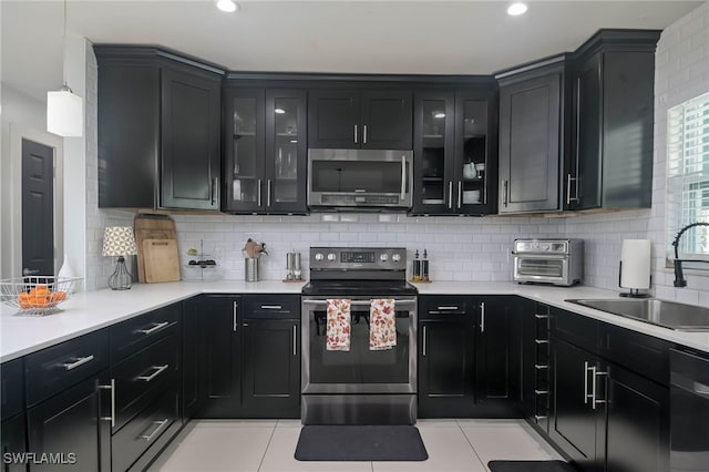 kitchen featuring light tile patterned floors, tasteful backsplash, appliances with stainless steel finishes, and sink