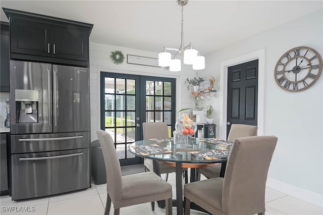 tiled dining room featuring a chandelier and french doors