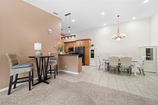 kitchen featuring black fridge, light tile patterned floors, kitchen peninsula, and hanging light fixtures