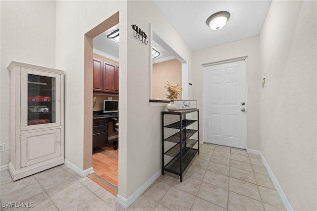 tiled entrance foyer with crown molding and built in desk