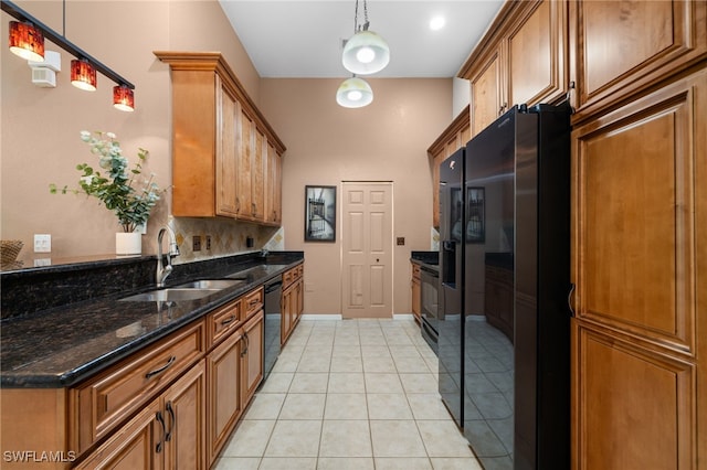 kitchen with black appliances, dark stone counters, sink, hanging light fixtures, and light tile patterned floors