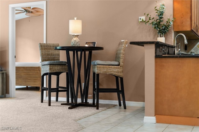 tiled dining space with ceiling fan, sink, and vaulted ceiling