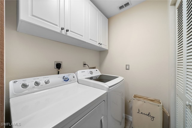 laundry room featuring washer and clothes dryer and cabinets