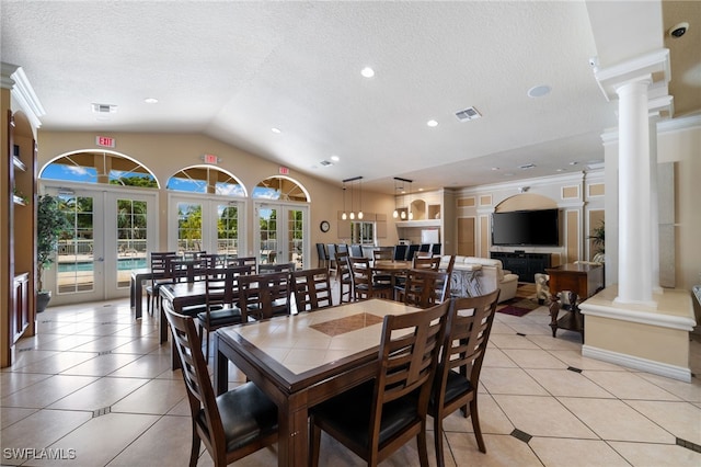 tiled dining room with a textured ceiling, crown molding, ornate columns, and french doors