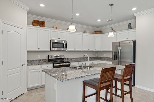 kitchen with hanging light fixtures, a kitchen island with sink, sink, and appliances with stainless steel finishes