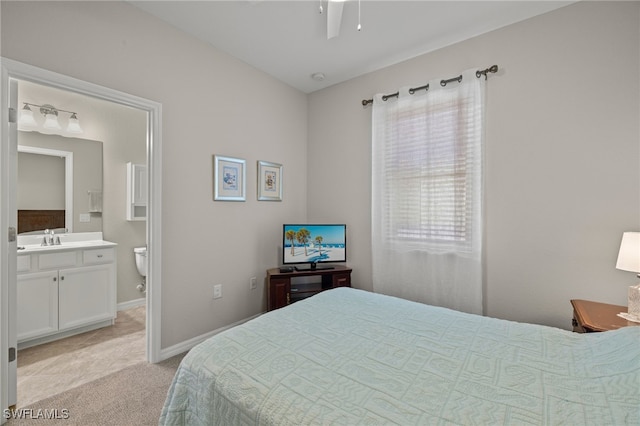 bedroom with ensuite bathroom, light colored carpet, and sink