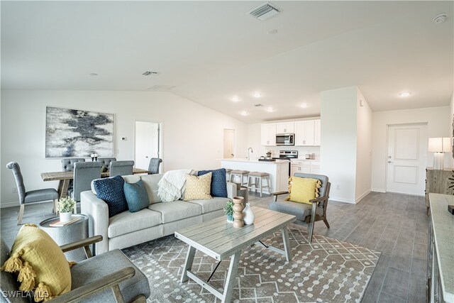 living room featuring sink, vaulted ceiling, and dark hardwood / wood-style flooring