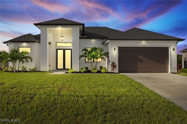 prairie-style home featuring stucco siding, driveway, a front lawn, and a garage