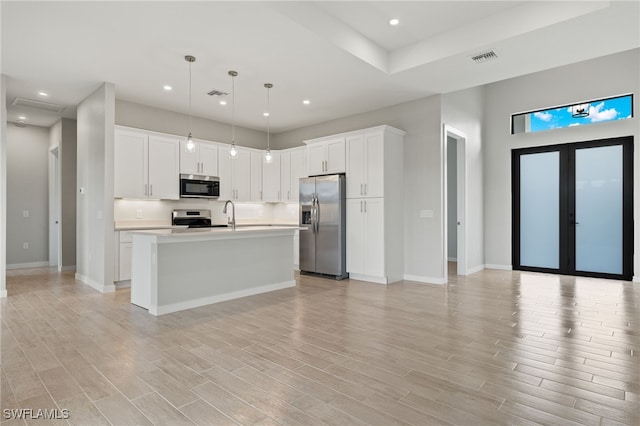 kitchen featuring visible vents, light countertops, white cabinets, light wood-style floors, and stainless steel appliances