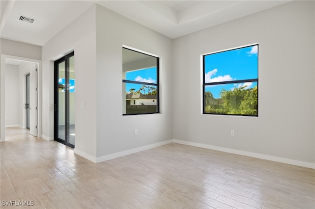unfurnished room with a healthy amount of sunlight, light wood finished floors, and visible vents