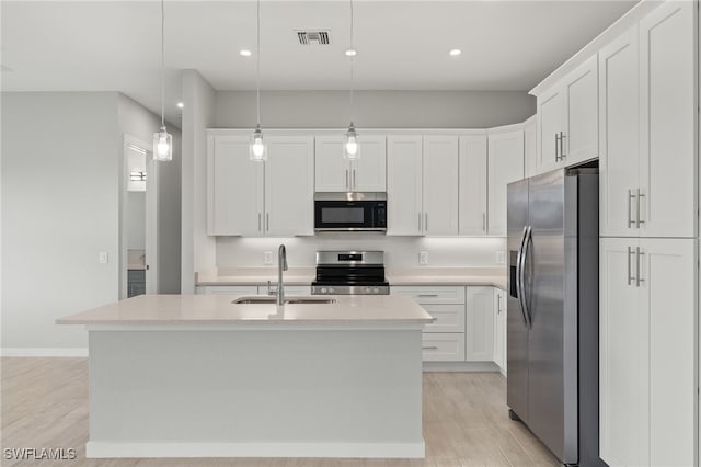 kitchen featuring appliances with stainless steel finishes, a sink, light wood finished floors, light countertops, and white cabinetry