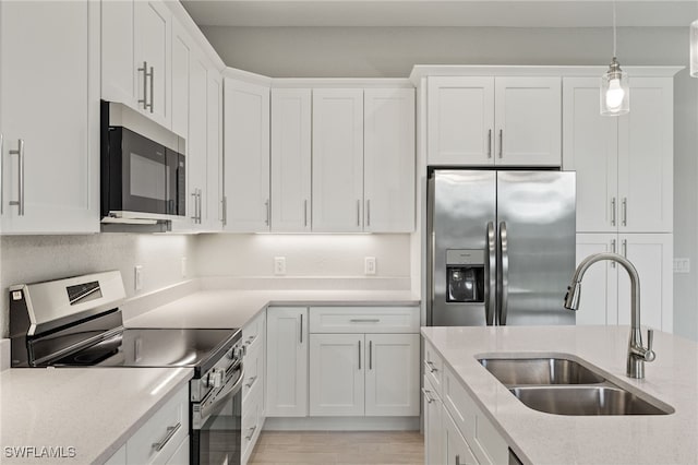 kitchen with white cabinets, stainless steel appliances, pendant lighting, and a sink