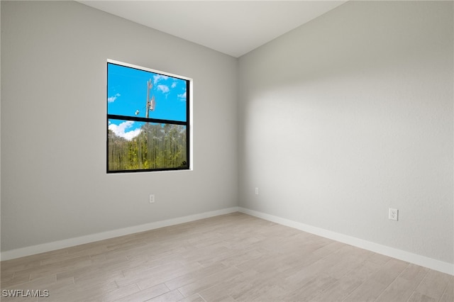 spare room with baseboards and wood finished floors