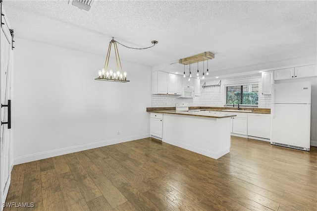 kitchen featuring dark hardwood / wood-style flooring, white cabinets, white appliances, and a barn door