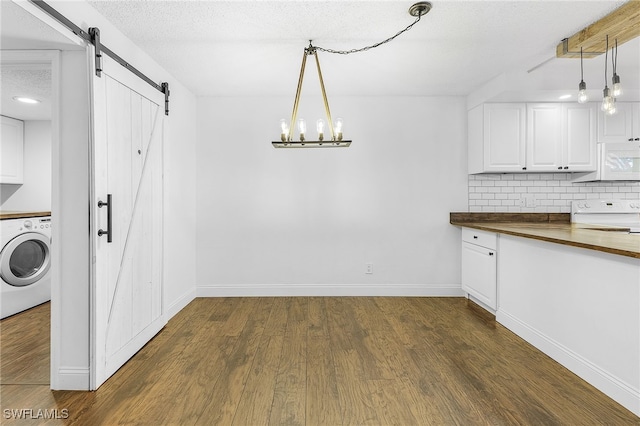 interior space featuring a textured ceiling, washer / clothes dryer, dark hardwood / wood-style floors, a notable chandelier, and a barn door