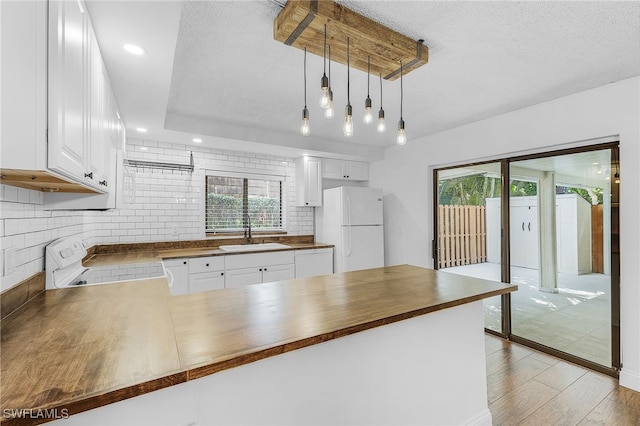 kitchen featuring kitchen peninsula, hanging light fixtures, white fridge, and wooden counters