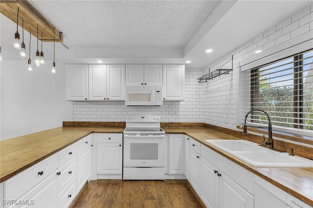 kitchen with white appliances, butcher block countertops, white cabinetry, and sink