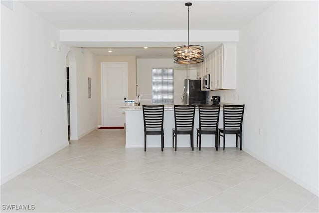 kitchen with pendant lighting, an inviting chandelier, a breakfast bar area, white cabinetry, and stainless steel appliances