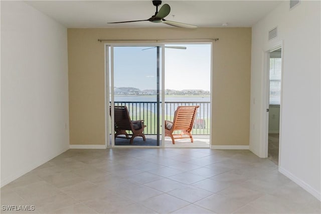 unfurnished room featuring ceiling fan, a healthy amount of sunlight, a water view, and light tile patterned flooring