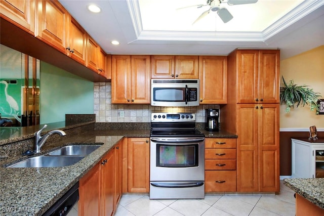 kitchen with sink, tasteful backsplash, a tray ceiling, stone counters, and stainless steel appliances