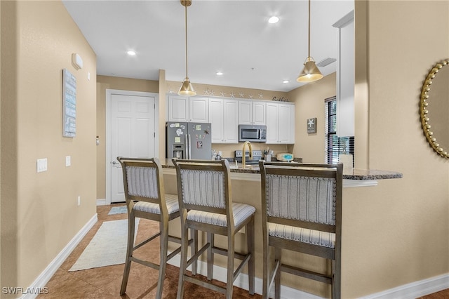 kitchen featuring decorative light fixtures, stainless steel appliances, kitchen peninsula, and white cabinets