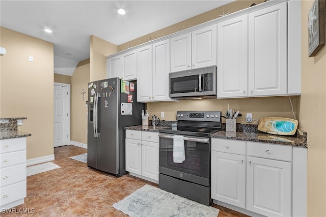 kitchen featuring dark stone countertops, stainless steel appliances, and white cabinetry