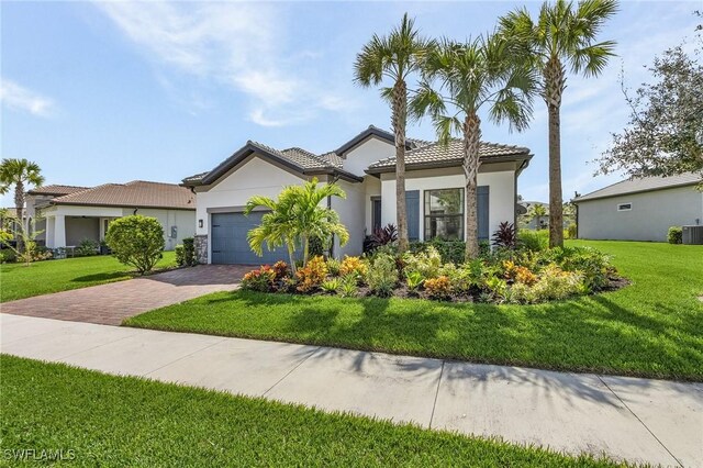 mediterranean / spanish-style house featuring central AC unit, a front yard, and a garage