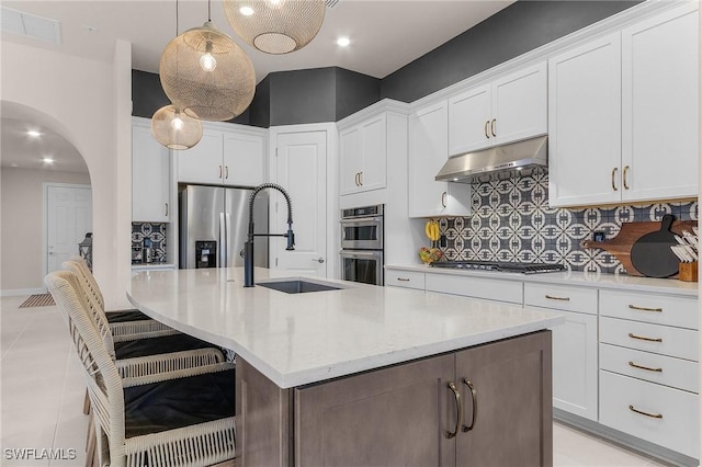 kitchen with white cabinetry, appliances with stainless steel finishes, an island with sink, and hanging light fixtures