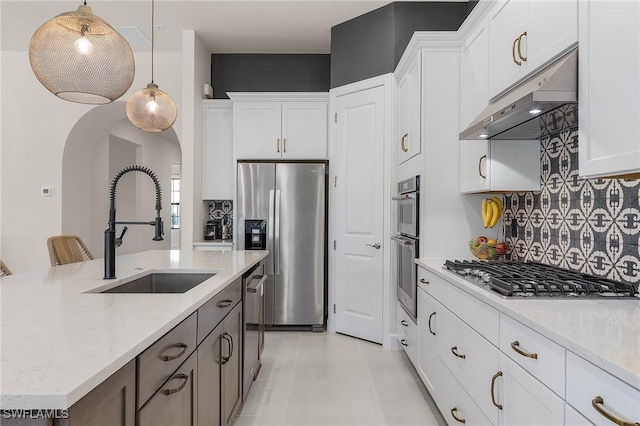 kitchen with sink, appliances with stainless steel finishes, light stone counters, white cabinets, and decorative light fixtures