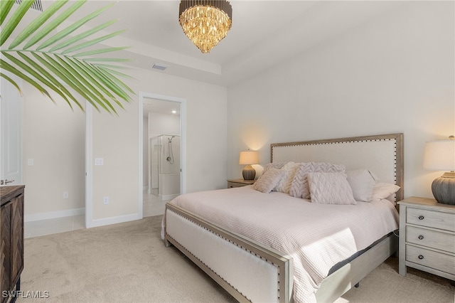 bedroom with ensuite bathroom, light carpet, an inviting chandelier, and a tray ceiling