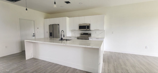 kitchen with light hardwood / wood-style floors, appliances with stainless steel finishes, sink, and white cabinetry