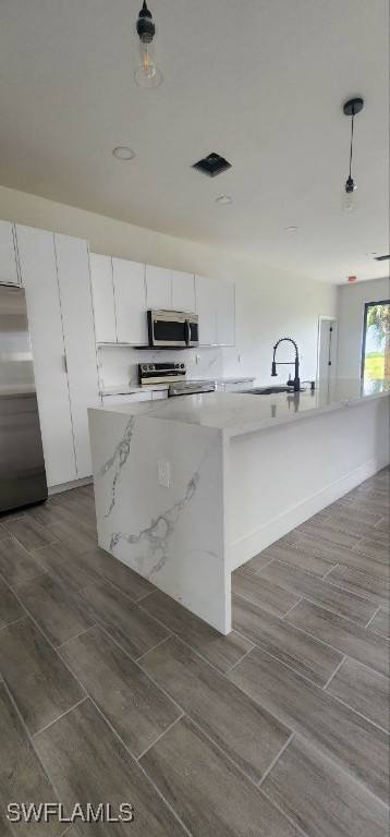 kitchen featuring an island with sink, white cabinetry, sink, and stainless steel appliances