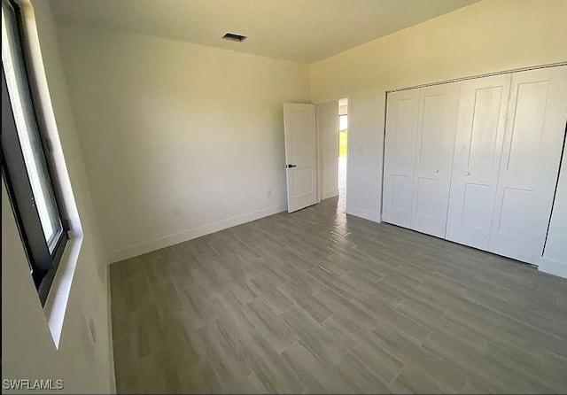 unfurnished bedroom featuring a closet and hardwood / wood-style flooring