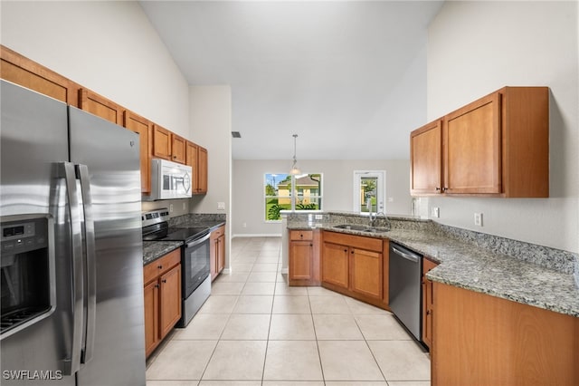 kitchen featuring sink, kitchen peninsula, appliances with stainless steel finishes, decorative light fixtures, and light tile patterned floors