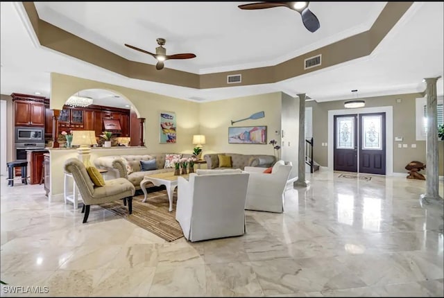 living room featuring ceiling fan, french doors, a tray ceiling, crown molding, and ornate columns