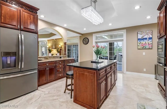 kitchen featuring hanging light fixtures, a kitchen island, stainless steel appliances, dark stone countertops, and a kitchen bar