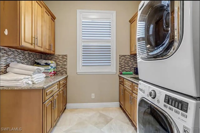 laundry room with stacked washing maching and dryer and cabinets