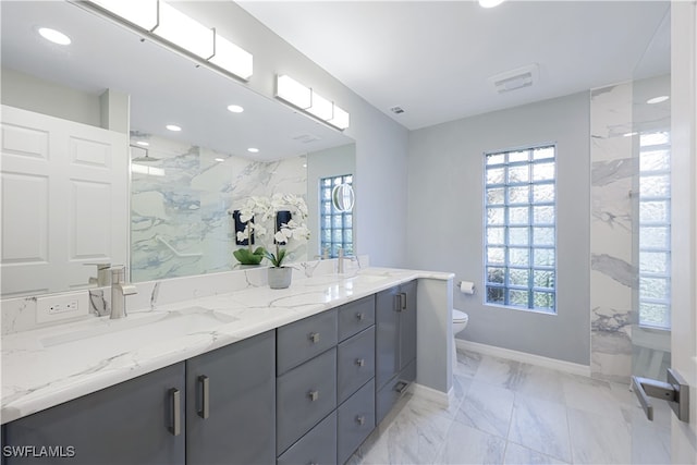 bathroom with tiled shower, vanity, and toilet