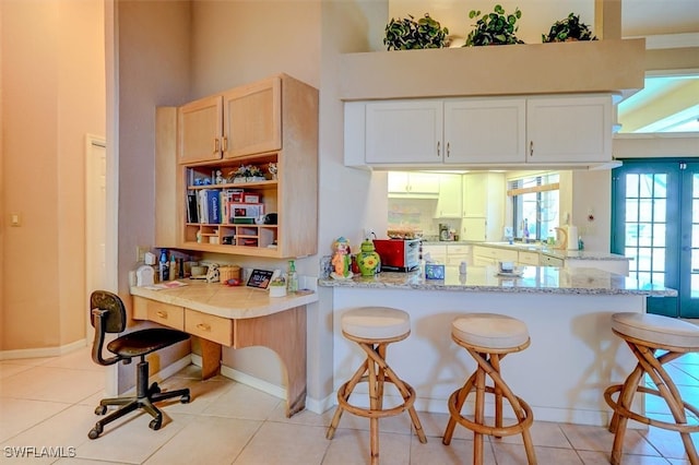 kitchen with kitchen peninsula, light tile patterned flooring, and a breakfast bar area