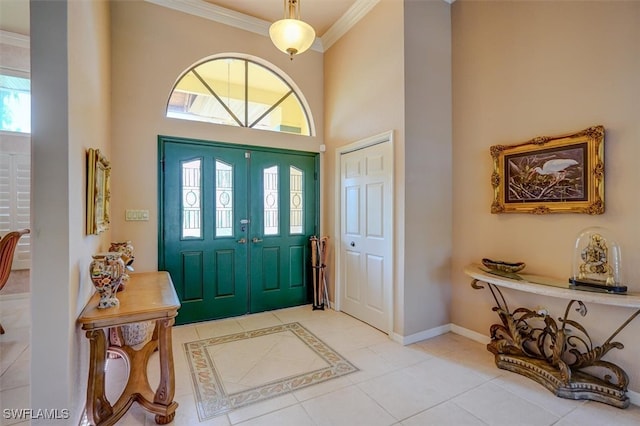 tiled entryway featuring crown molding and a high ceiling