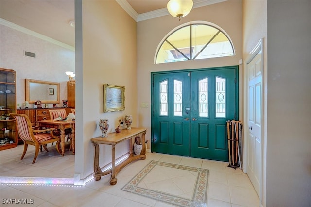 entryway with a high ceiling, ornamental molding, and light tile patterned floors