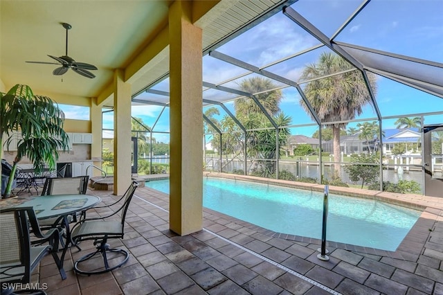 view of pool with a water view, ceiling fan, a patio area, and glass enclosure