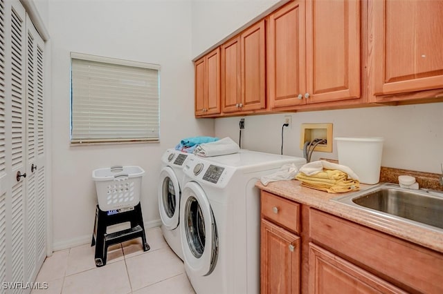 washroom with washer and clothes dryer, sink, light tile patterned floors, and cabinets