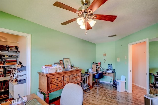 home office with light wood-type flooring and ceiling fan