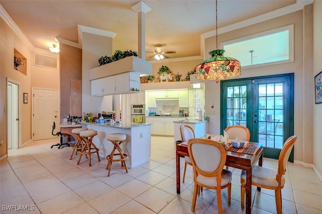 dining room with ceiling fan, a towering ceiling, light tile patterned floors, and crown molding