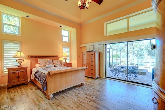 bedroom with light hardwood / wood-style flooring, a towering ceiling, access to exterior, and ornamental molding