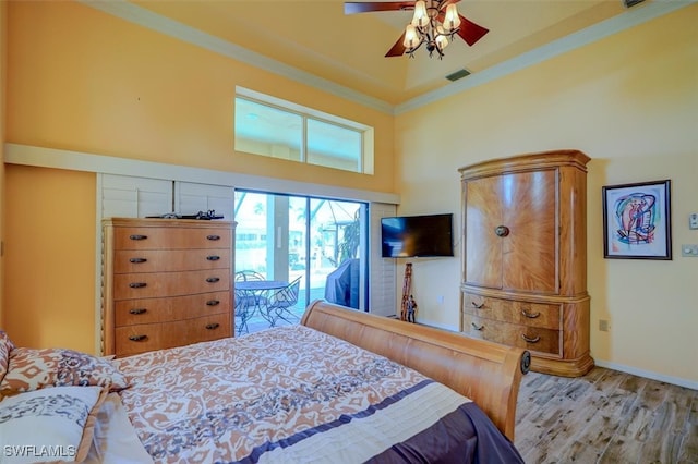 bedroom with ceiling fan, light hardwood / wood-style flooring, a high ceiling, crown molding, and access to exterior