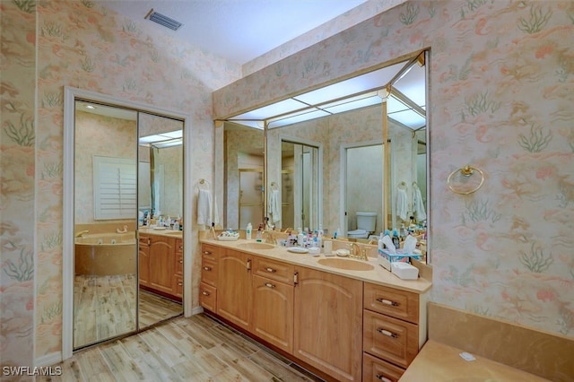 bathroom featuring a tub to relax in, hardwood / wood-style floors, vanity, and toilet