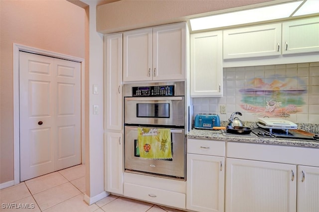 kitchen with white cabinetry, stainless steel double oven, light stone counters, and tasteful backsplash