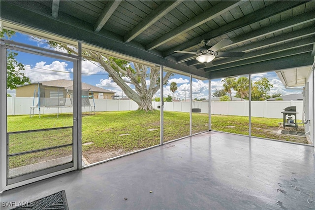 unfurnished sunroom with ceiling fan, beamed ceiling, and a healthy amount of sunlight